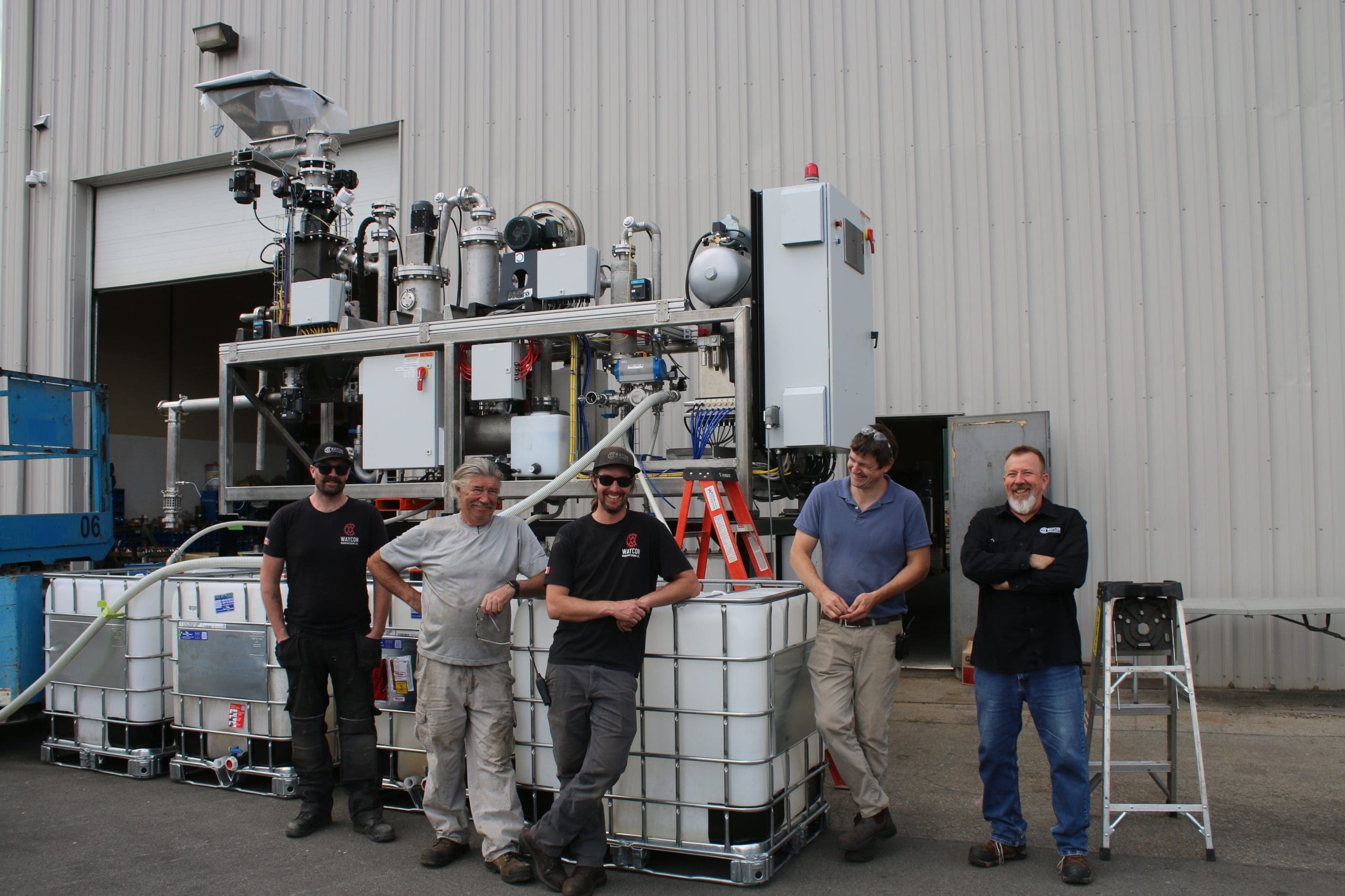 Waycon Employees standing with custom Waste Management Equipment Project